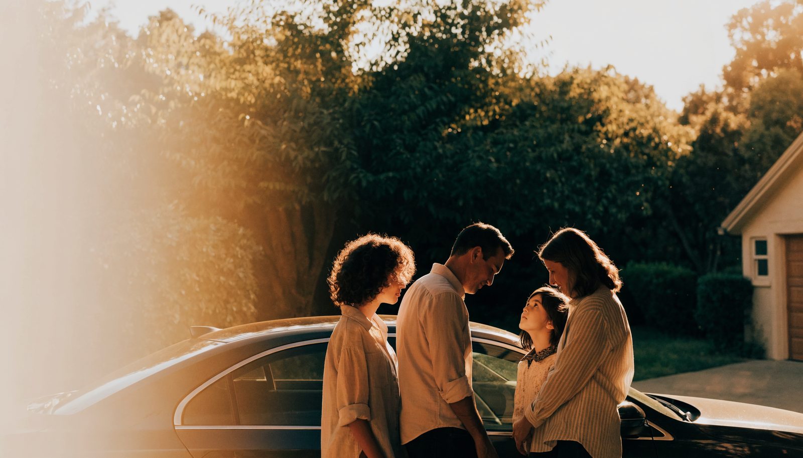 A California family standing beside their car at golden hour